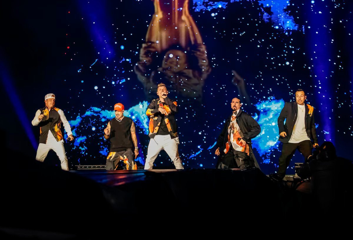 Backstreet Boys se apresentam no festival The Town 2025 em São Paulo, com os cinco integrantes no palco cantando e dançando diante de um telão iluminado com efeitos de estrelas. (Montagem com o vídeo de Can You Feel It ao fundo)