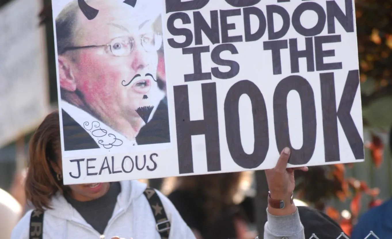 O DOSSIÊ SNEDDON — Parte V: O acordo de 1994: por que o caso terminou em um acordo civil? 1 Uma fã não identificada de Michael Jackson segura um cartaz contra o promotor público Tom Sneddon para demonstrar seu apoio.